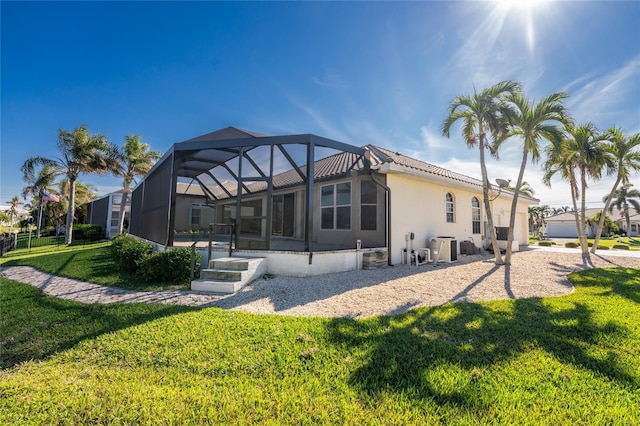 back of property featuring glass enclosure and a yard