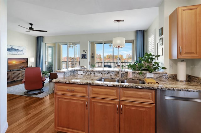 kitchen with sink, hanging light fixtures, stainless steel dishwasher, ceiling fan, and light wood-type flooring