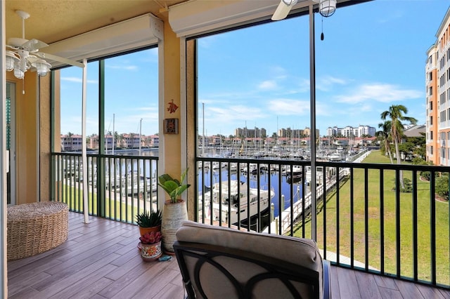 sunroom / solarium with ceiling fan and a water view