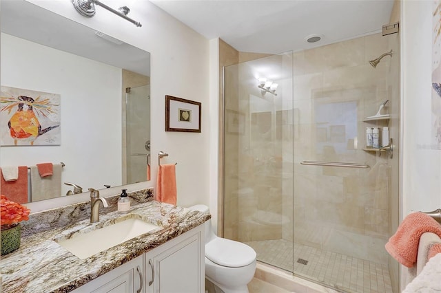 bathroom with vanity, a shower with shower door, and toilet