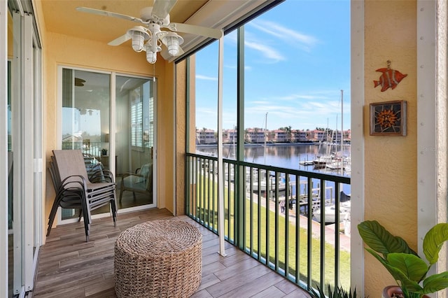 sunroom / solarium featuring a water view and ceiling fan