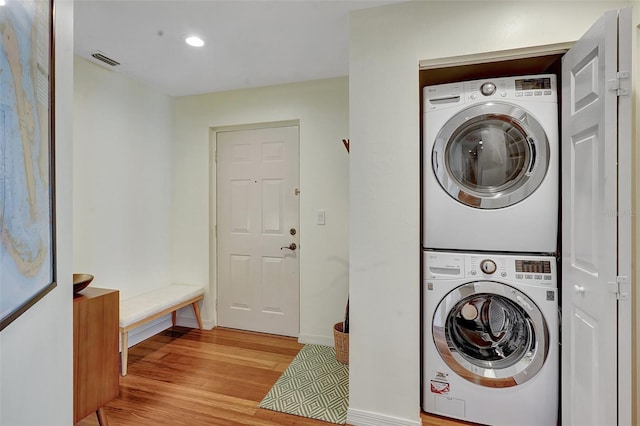 laundry area featuring stacked washer and dryer and light wood-type flooring