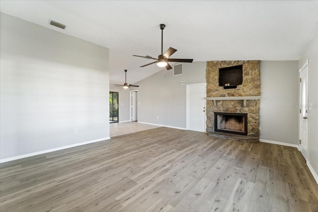 unfurnished living room featuring ceiling fan, a fireplace, vaulted ceiling, and light wood-type flooring