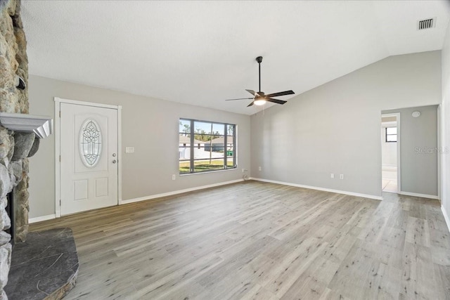 unfurnished living room with ceiling fan, a fireplace, light hardwood / wood-style floors, and vaulted ceiling