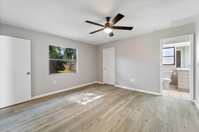21047 Baffin Ave, Port Charlotte, FL 33954 - unfurnished bedroom with multiple windows, light wood-style flooring, ensuite bathroom, and a ceiling fan
