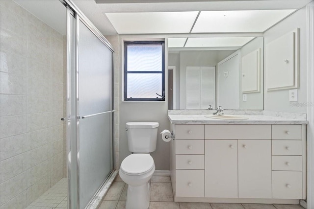 bathroom with tile patterned floors, vanity, an enclosed shower, and toilet