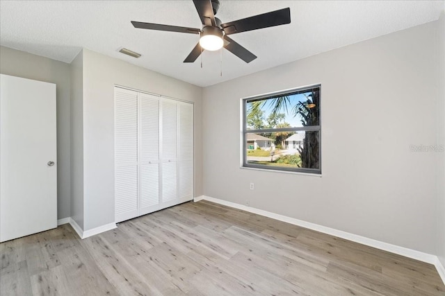 unfurnished bedroom with a closet, ceiling fan, light hardwood / wood-style flooring, and a textured ceiling