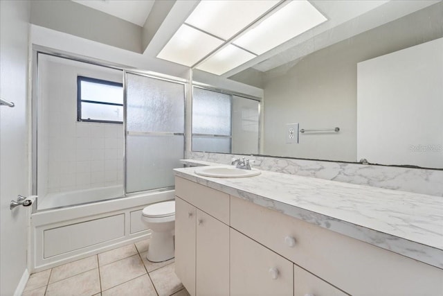 full bathroom with tile patterned flooring, vanity, combined bath / shower with glass door, and toilet