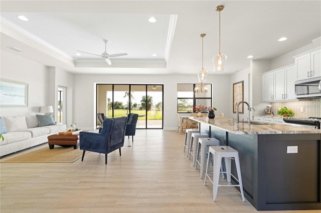 kitchen featuring sink, hanging light fixtures, light hardwood / wood-style flooring, light stone counters, and white cabinetry