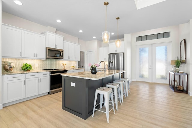 kitchen with white cabinetry, an island with sink, and appliances with stainless steel finishes