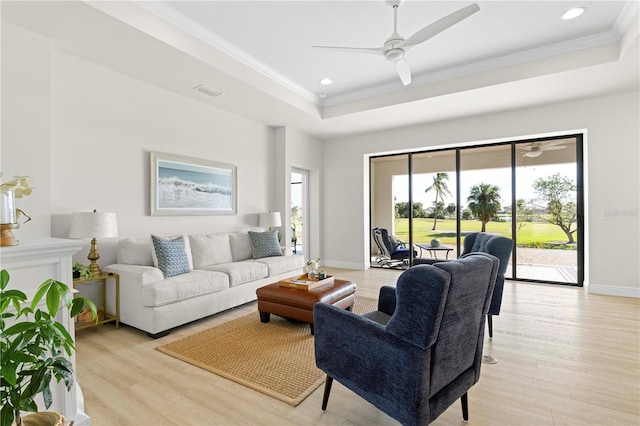 living room with ceiling fan, light hardwood / wood-style floors, crown molding, and a tray ceiling