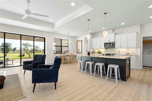 kitchen with white cabinets, ceiling fan with notable chandelier, stainless steel appliances, and light stone countertops