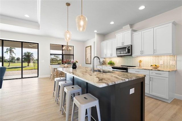 kitchen with appliances with stainless steel finishes, white cabinetry, pendant lighting, and sink