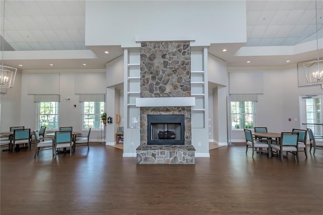 living room with dark hardwood / wood-style floors, a healthy amount of sunlight, a stone fireplace, and a high ceiling