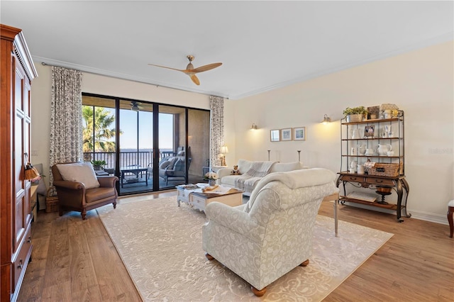 living room featuring ceiling fan, crown molding, and light hardwood / wood-style flooring