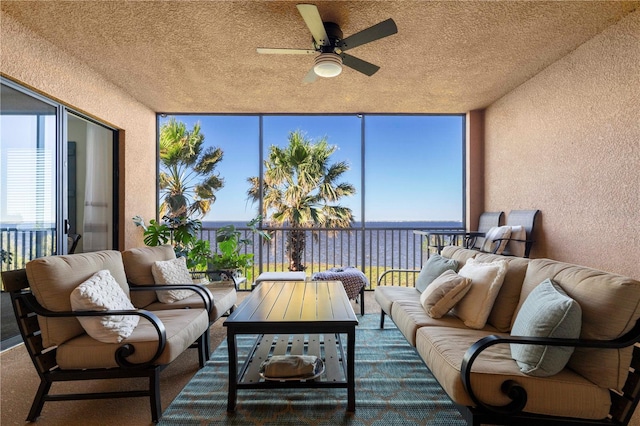 sunroom / solarium featuring a water view and ceiling fan