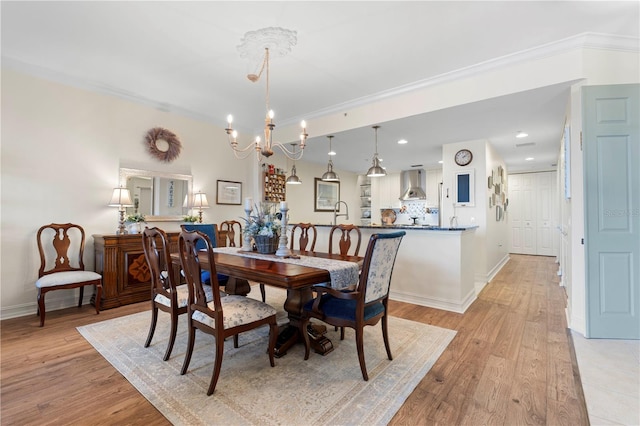 dining space with ornamental molding, light hardwood / wood-style floors, and a notable chandelier