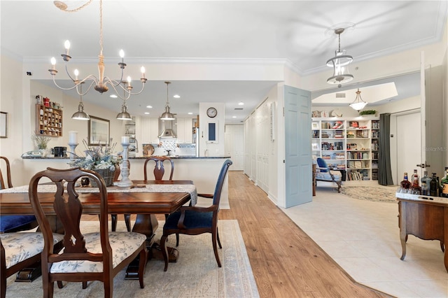 dining room with light wood-type flooring, an inviting chandelier, and crown molding