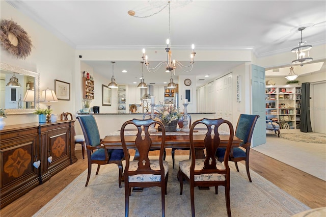 dining room with light wood-type flooring, ornamental molding, and an inviting chandelier