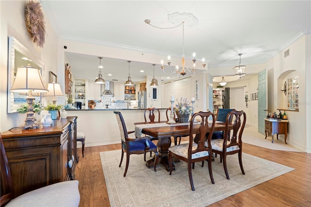 dining area with a notable chandelier, crown molding, and light hardwood / wood-style flooring