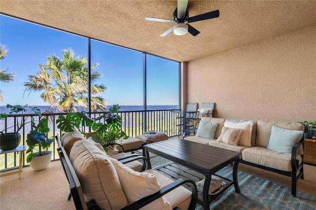 sunroom / solarium featuring ceiling fan and a water view