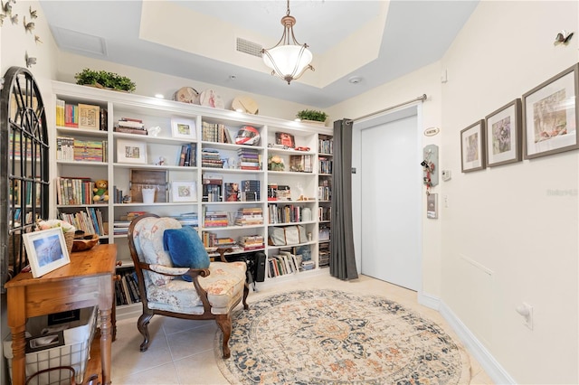 sitting room featuring light tile patterned floors and a raised ceiling