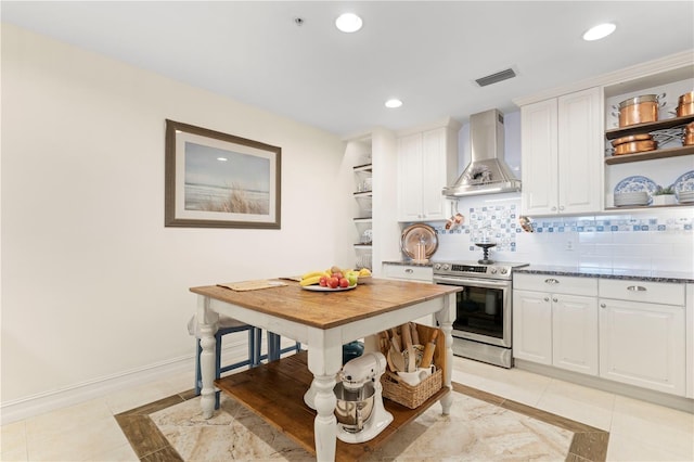 kitchen featuring stainless steel range with electric stovetop, dark stone counters, white cabinets, wall chimney exhaust hood, and tasteful backsplash