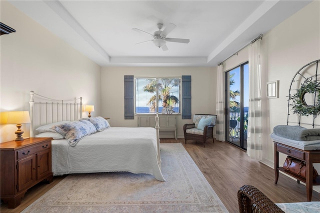 bedroom featuring ceiling fan, a tray ceiling, and light hardwood / wood-style flooring