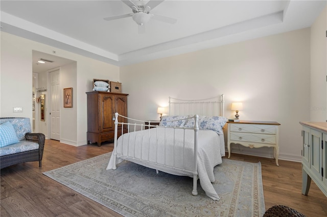 bedroom featuring wood-type flooring, a tray ceiling, and ceiling fan