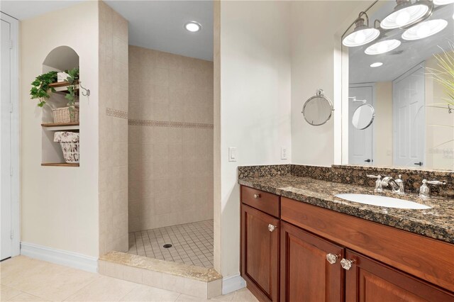 bathroom with tile patterned floors, vanity, and tiled shower