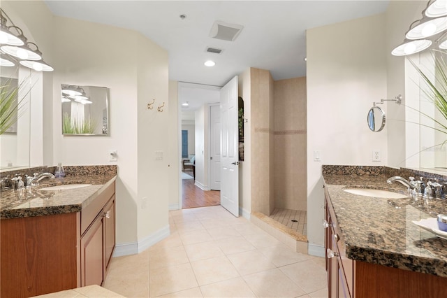 bathroom with tiled shower, vanity, and tile patterned flooring