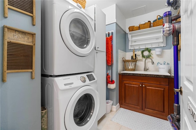 clothes washing area with stacked washer and dryer, light tile patterned flooring, cabinets, and sink