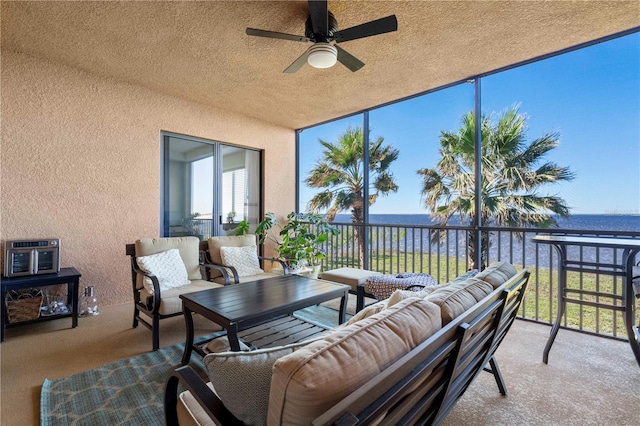 sunroom / solarium featuring ceiling fan and a water view