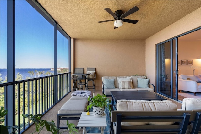 sunroom / solarium with ceiling fan and a water view