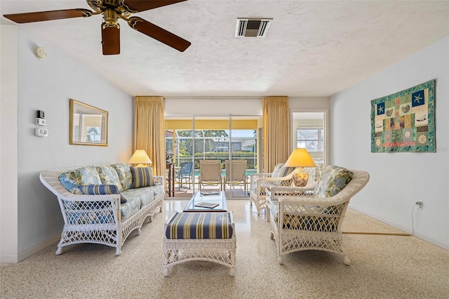 living room with ceiling fan and a textured ceiling