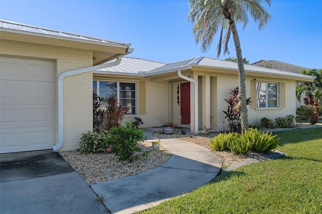 view of exterior entry featuring a lawn and a garage