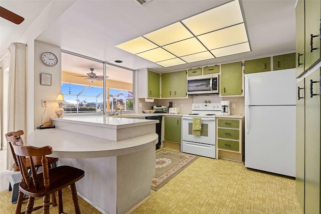 kitchen with ceiling fan, green cabinets, kitchen peninsula, white appliances, and a breakfast bar area