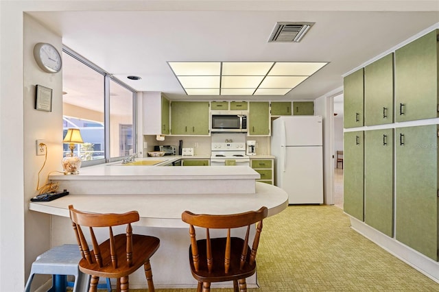 kitchen featuring kitchen peninsula, a kitchen breakfast bar, white appliances, sink, and green cabinetry