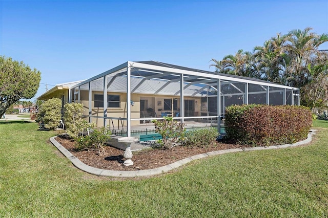 rear view of property featuring a lawn and glass enclosure