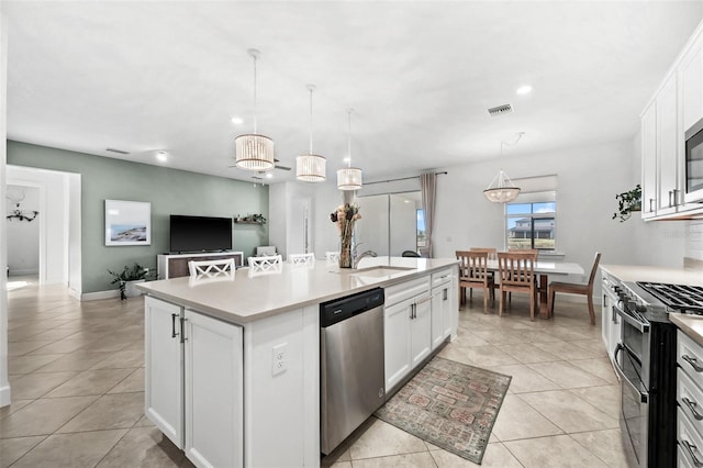 kitchen with a kitchen island with sink, hanging light fixtures, white cabinets, and stainless steel appliances