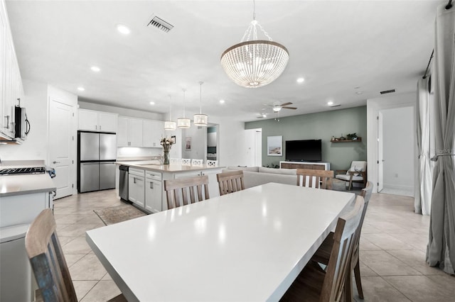 tiled dining space featuring sink and ceiling fan with notable chandelier