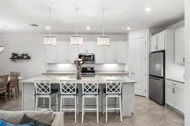 kitchen featuring white cabinetry, a center island with sink, stainless steel appliances, and decorative light fixtures