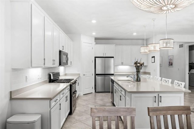 kitchen featuring appliances with stainless steel finishes, a kitchen island with sink, sink, pendant lighting, and white cabinetry