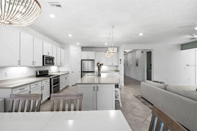 kitchen with white cabinets, a kitchen breakfast bar, hanging light fixtures, appliances with stainless steel finishes, and a kitchen island