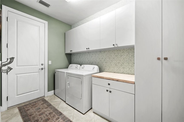 laundry room featuring washer and clothes dryer, cabinets, and light tile patterned floors