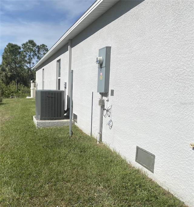 view of side of home with central AC and a lawn