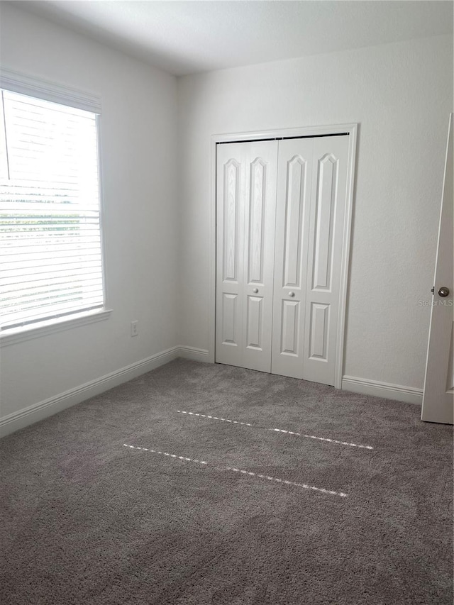 unfurnished bedroom with dark carpet and a closet