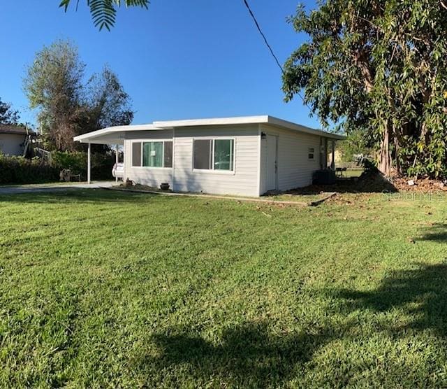 view of side of property with a carport and a lawn