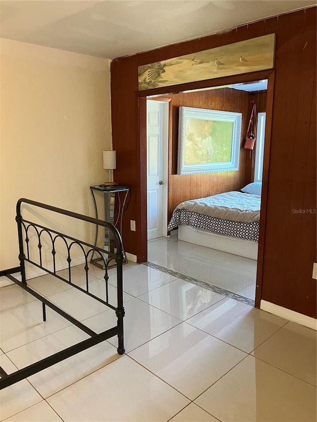 bedroom with light tile patterned flooring and wood walls