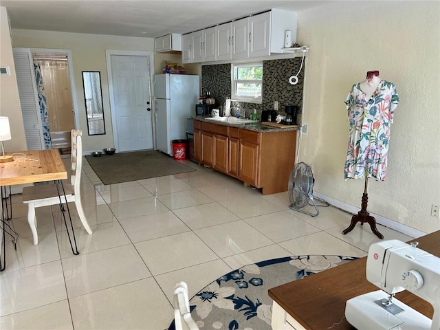 kitchen featuring tasteful backsplash, white cabinetry, sink, white refrigerator, and light tile patterned floors